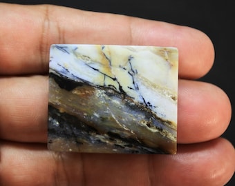 May include: A square-shaped polished gemstone cabochon featuring a marbled pattern of creamy white, tan, and dark brown colors with distinct black dendritic inclusions running diagonally across the smooth, glossy surface of the stone.