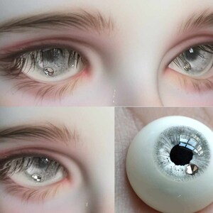May include: Close-up of a pair of realistic doll eyes with a silver glitter effect. The eyes are set in a doll's head and have a white sclera and a black pupil. The eyes are surrounded by eyelashes and a light pink eyelid.
