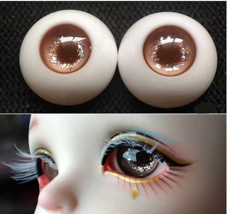 May include: Two brown and white doll eyes with glitter accents. The eyes are closed and have a light brown iris with a dark brown pupil.