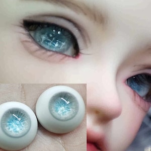 May include: Two blue and white doll eyes with a sparkly finish. The eyes are on a white background.