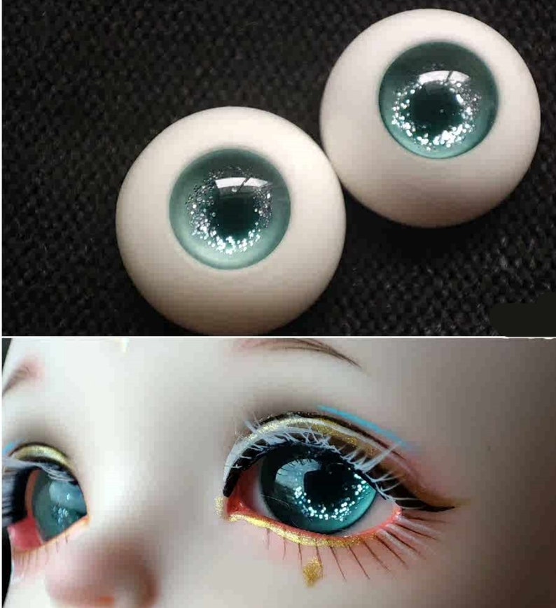 May include: Two blue doll eyes with silver glitter. The eyes are on a white background.