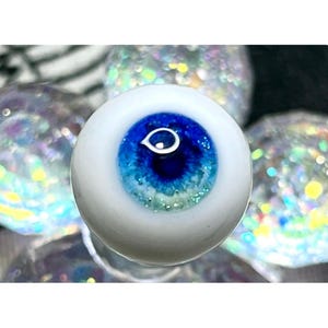 Puede incluir: Primer plano de un ojo de muñeca azul y blanco con un iris blanco y una pupila azul.