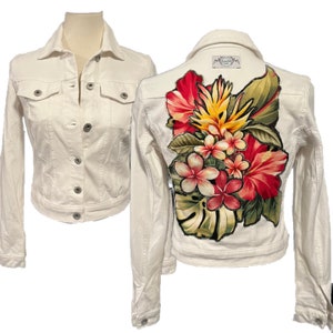 May include: Off-white denim jacket with a button-up front and two chest pockets. The back of the jacket features a vibrant floral design with red, pink, yellow, and green flowers and leaves. The jacket is displayed on a mannequin.