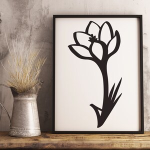 K&ouml;nnte beinhalten: Schwarz-wei&szlig;e Silhouette einer Krokusbl&uuml;te in einem schwarzen Rahmen. Die Blume ist stilisiert und hat ein einfaches Design.