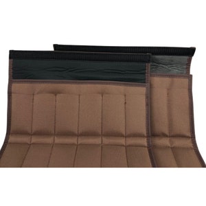 May include: Two brown fabric wraps with a series of stitched vertical lines. The wraps have a black band at the top with a hook and loop closure. The edges are trimmed with a darker brown material.