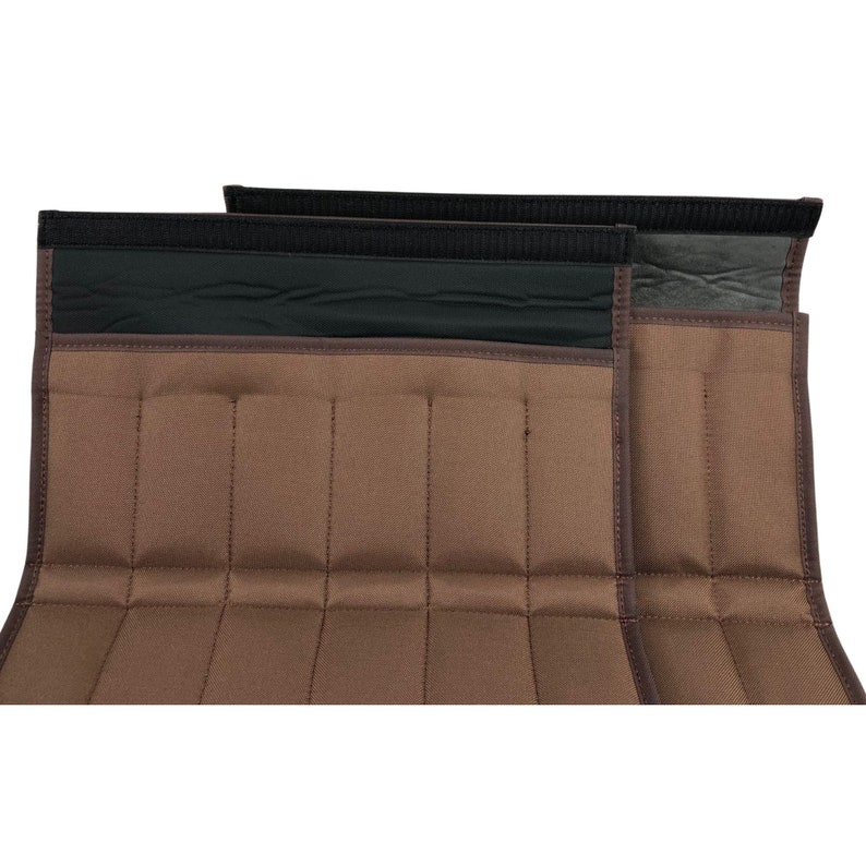 May include: Two brown fabric wraps with a series of stitched vertical lines. The wraps have a black band at the top with a hook and loop closure. The edges are trimmed with a darker brown material.