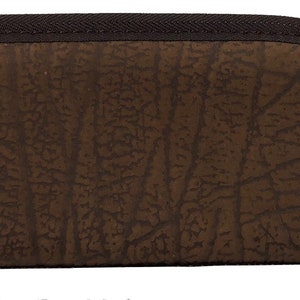 May include: A brown, semi-circular eyeglasses case with a textured surface. The case has a dark brown zipper and trim. The textured pattern resembles a tree bark design. The case is designed to protect eyeglasses.
