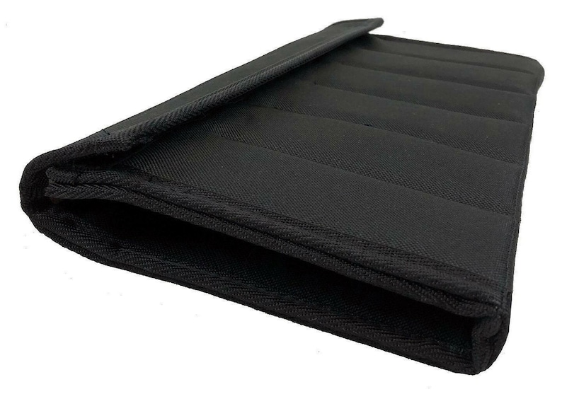 May include: Black, rectangular padded case with a flap. The case is made of a textured fabric and features several parallel, stitched lines across its surface. The edges are neatly finished with a contrasting trim.