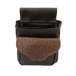 May include: A dark brown leather pouch with a flap closure. The pouch has a contrasting brown ostrich-style leather pocket on the front. The interior is visible, revealing multiple compartments. The stitching is a lighter brown color.