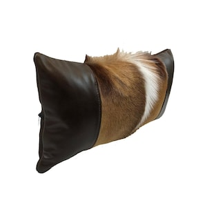 May include: A brown leather and brown and white fur pillow. The pillow has a zipper closure.