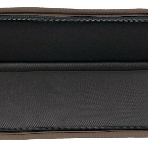 May include: Open, brown, zippered case with a black interior. The case is oval-shaped and has a black zipper. The interior is lined with a textured black fabric. The zipper pull is black.