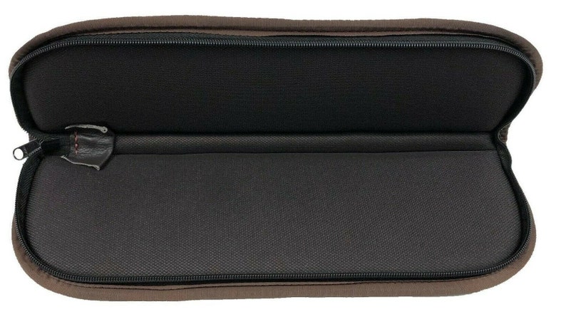 May include: Open, brown, zippered case with a black interior. The case is oval-shaped and has a black zipper. The interior is lined with a textured black fabric. The zipper pull is black.