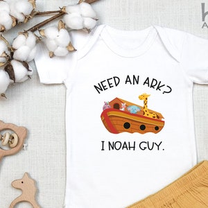 May include: White baby onesie with a cartoon ark and animals. The text reads "Need an ark? I Noah guy."