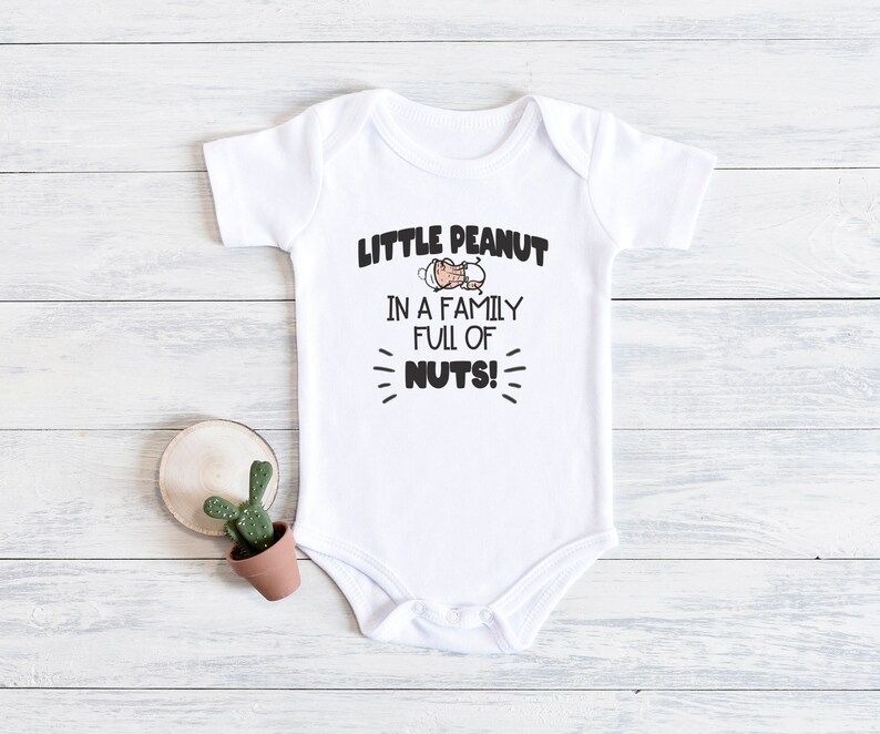 May include: White baby onesie with a cartoon peanut and the text "Little Peanut in a family full of nuts!"