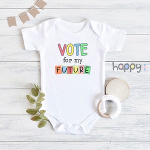 May include: White baby onesie with short sleeves featuring the text "VOTE for my FUTURE" in colorful block letters.
