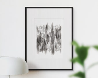 May include: A black and white abstract art print in a black frame, hanging on a white wall above a desk with a lamp, a succulent plant, a laptop, and a stack of books.