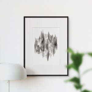 Könnte beinhalten: Ein Schwarz-Weiß-Abstrakt-Kunstdruck in einem schwarzen Rahmen, der an einer weißen Wand über einem Schreibtisch mit einer Lampe, einer Topfpflanze, einem Laptop und einem Stapel Büchern hängt.