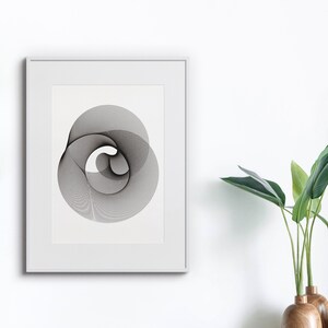 Può includere: Un design geometrico astratto in bianco e nero in una cornice bianca su una parete bianca. Una pianta in vaso con foglie verdi è su uno scaffale in legno sotto l'opera incorniciata.