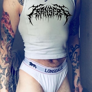Op de afbeelding: Een wit tanktop met een zwart bandlogo met de tekst "Terrorizer". Het tanktop wordt gedragen door een persoon met tatoeages op zijn armen.