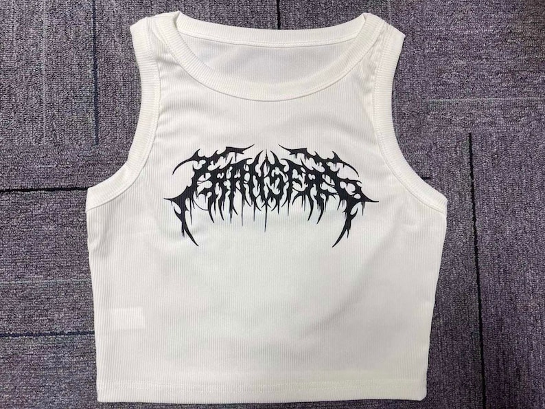 Op de afbeelding: Witte geribbelde tanktop met een zwarte grafische print van het woord "FANGS" in een gotisch lettertype.