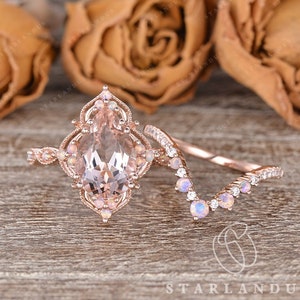May include: A rose gold engagement ring set with a pear-shaped morganite center stone and a matching contoured wedding band with pave set diamonds and opals.