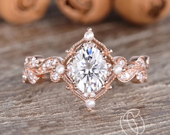 Puede incluir: Un anillo de compromiso de oro rosa con una gran piedra central ovalada rodeada de diamantes y perlas más pequeños. El anillo presenta un delicado diseño floral con intrincados detalles.