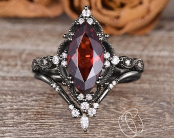 May include: A black metal ring featuring a large marquise-cut deep red garnet gemstone at the center. The setting is adorned with numerous small, clear round-cut stones arranged in a decorative, intricate pattern along the band and the halo.