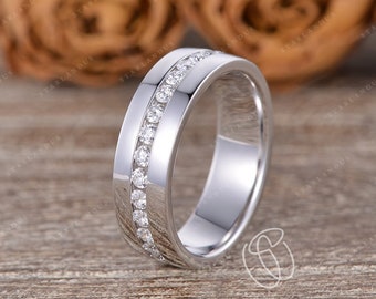 May include: A silver wedding band with a row of small diamonds set in the band.