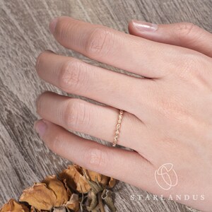 Op de afbeelding: Een delicate gouden ring met een rij kleine, ronde diamanten in pav&eacute;-zetting.