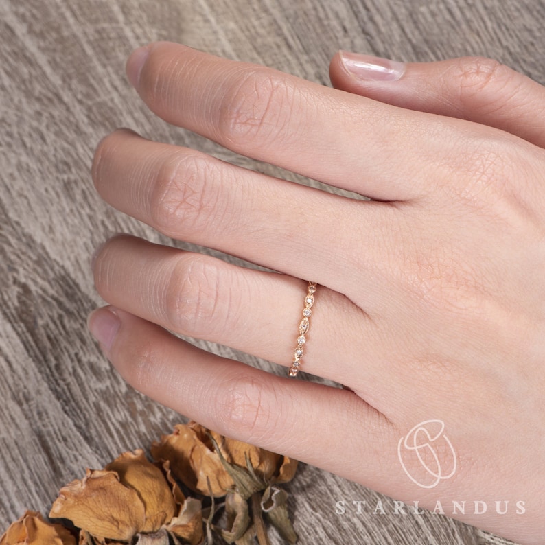 Op de afbeelding: Een delicate gouden ring met een rij kleine, ronde diamanten in pav&eacute;-zetting.