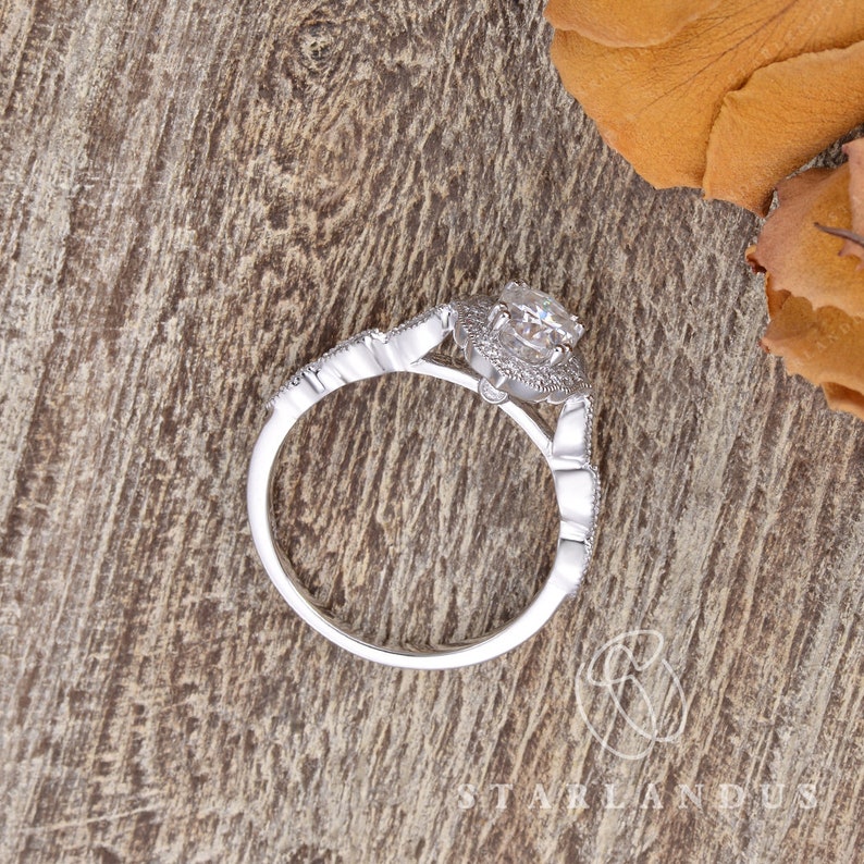 May include: A silver ring with a large, round, clear gemstone surrounded by smaller gemstones. The ring has a delicate, intricate design.