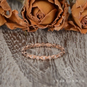 Op de afbeelding: Een delicate ros&eacute;gouden trouwring met een gegolfde rand en kleine diamanten in pav&eacute;-zetting.