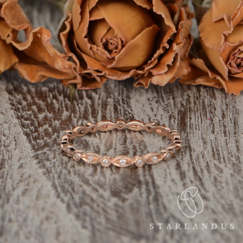 Op de afbeelding: Een delicate ros&eacute;gouden trouwring met een gegolfde rand en kleine diamanten in pav&eacute;-zetting.