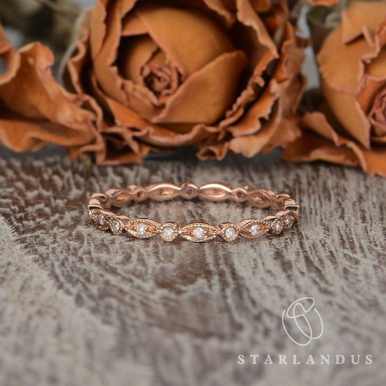Op de afbeelding: Een delicate ros&eacute;gouden trouwring met een rij kleine, ronde diamanten gezet in een vintage-ge&iuml;nspireerd ontwerp.