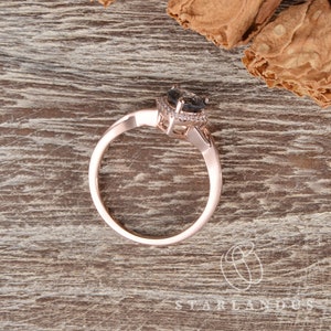 May include: A rose gold engagement ring with a black gemstone surrounded by a halo of smaller diamonds.
