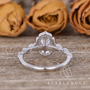 May include: A silver engagement ring with a large, oval-shaped center stone and a delicate, intricate design. The ring is set with smaller diamonds around the center stone and on the band.