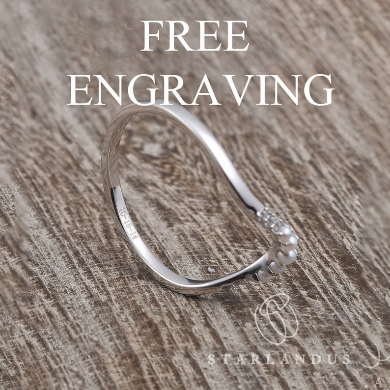 May include: A silver ring with a curved design and a row of small white stones. The ring is engraved with the text "1G-15-14" and "STARLANDUS".
