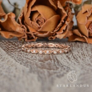 Op de afbeelding: Een delicate band van ros&eacute;goud met een vintage-ge&iuml;nspireerd ontwerp met kleine ronde diamanten die in een gegolfd patroon zijn gezet.