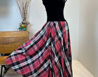 May include: A black velvet bodice with a scoop neckline and cap sleeves is attached to a red, black, and white plaid skirt. The skirt is full and flowing.