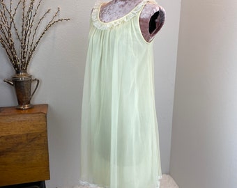 May include: A pale yellow, sheer nightgown with a lace trim around the neckline and hem. The nightgown is on a mannequin and has a sleeveless design.