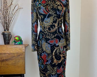 May include: A black sequined dress with a floral pattern in shades of red, gold, blue, and green. The dress has long sleeves and a fitted silhouette.