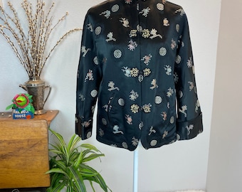 May include: A black silk jacket with a mandarin collar and gold and silver embroidery. The jacket has a floral pattern and multiple buttons.