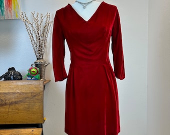 May include: A red velvet dress with a v-neckline and three-quarter sleeves. The dress is fitted at the waist and has a flared skirt.