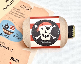 Puede incluir: Un tubo de papel marrón con una etiqueta a rayas rojas y blancas. La etiqueta presenta una calavera en blanco y negro con un parche en el ojo y huesos cruzados. El texto "Lukas" y "Einladung" están en la etiqueta.