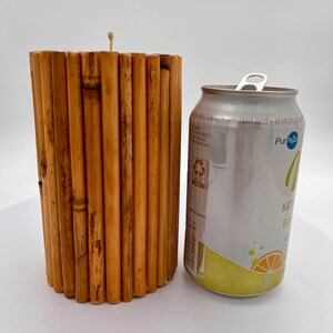 May include: A brown bamboo candle holder with a white candle wick. The candle holder is next to a silver can of Pure Leaf Natural Flavored Iced Tea.
