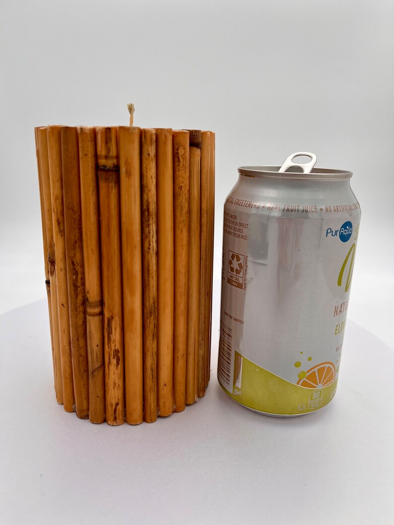 May include: A brown bamboo candle holder with a white candle wick. The candle holder is next to a silver can of Pure Leaf Natural Flavored Iced Tea.