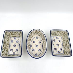 May include: Three ceramic serving dishes with a floral design. The dishes are white with blue and orange flowers, and a blue border. The two rectangular dishes are 8 inches long, and the oval dish is 9 inches long.