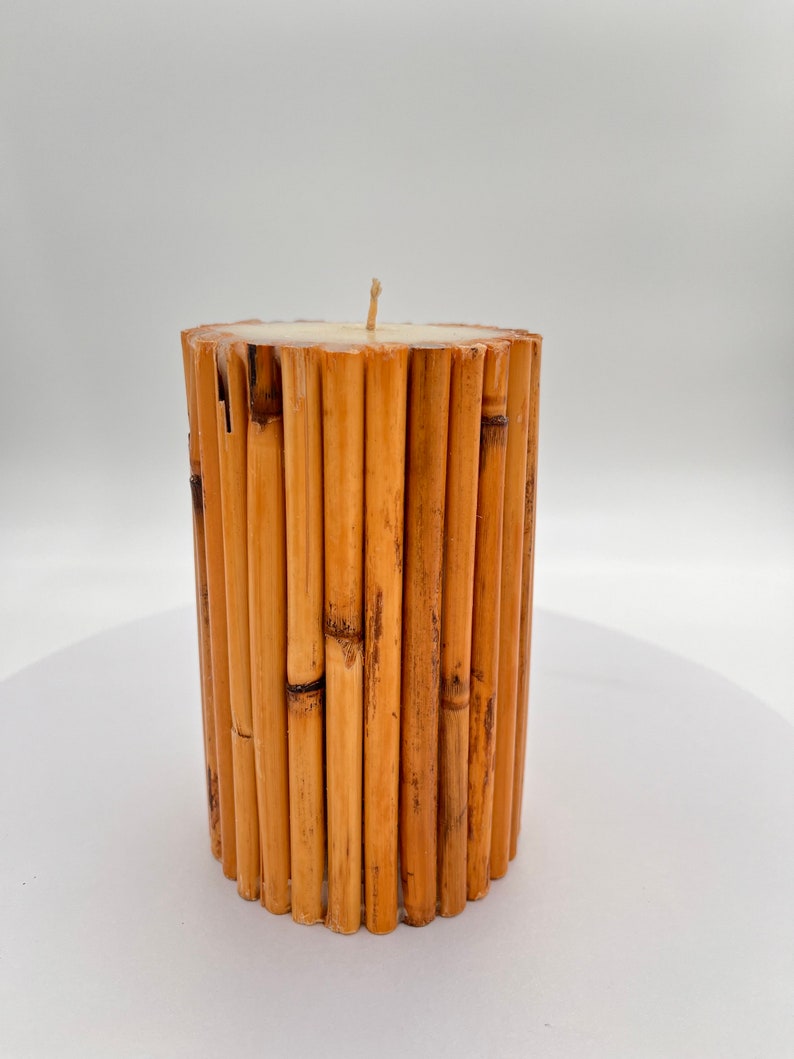 May include: A cylindrical candle made of natural bamboo sticks. The candle is white and has a single wick.