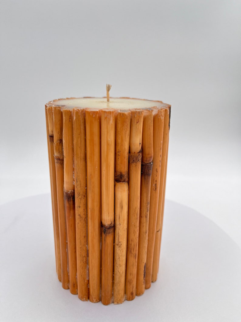 May include: A cylindrical candle made of natural bamboo sticks. The candle is white and has a single wick.