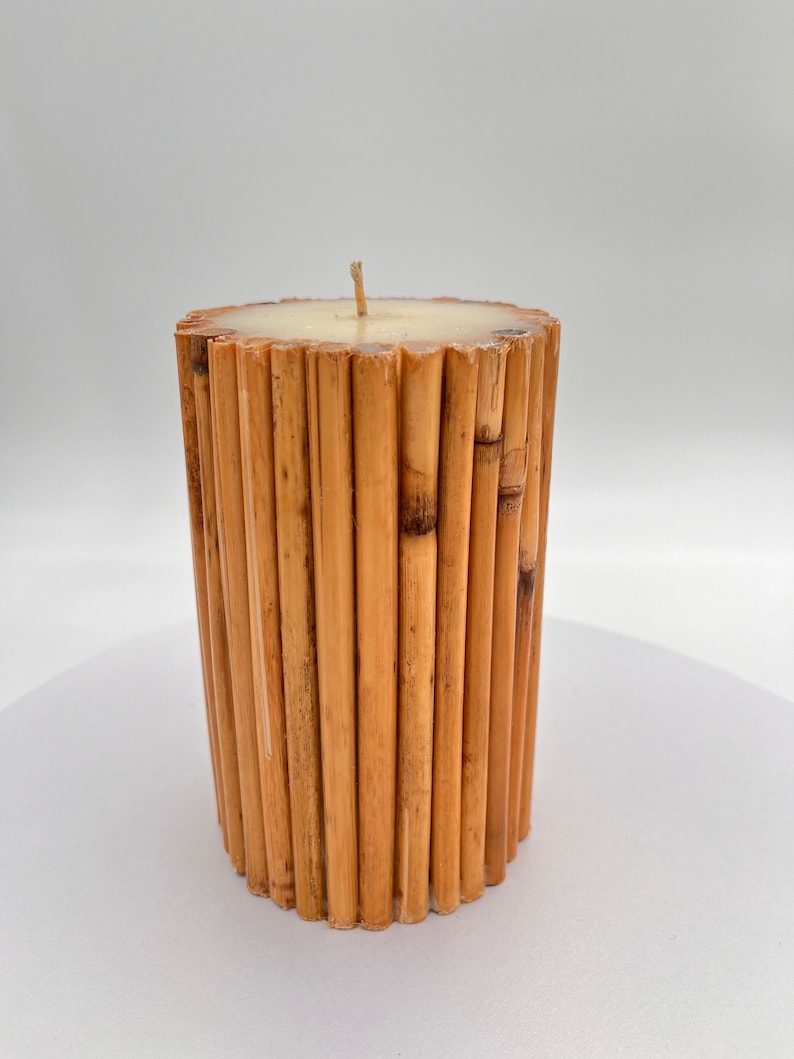 May include: A cylindrical candle made of natural bamboo sticks, with a white wax top and a single wick.